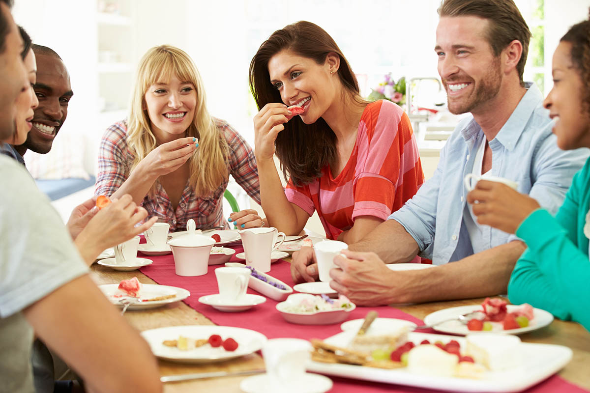 Happy people sitting at a table eating food and talking.