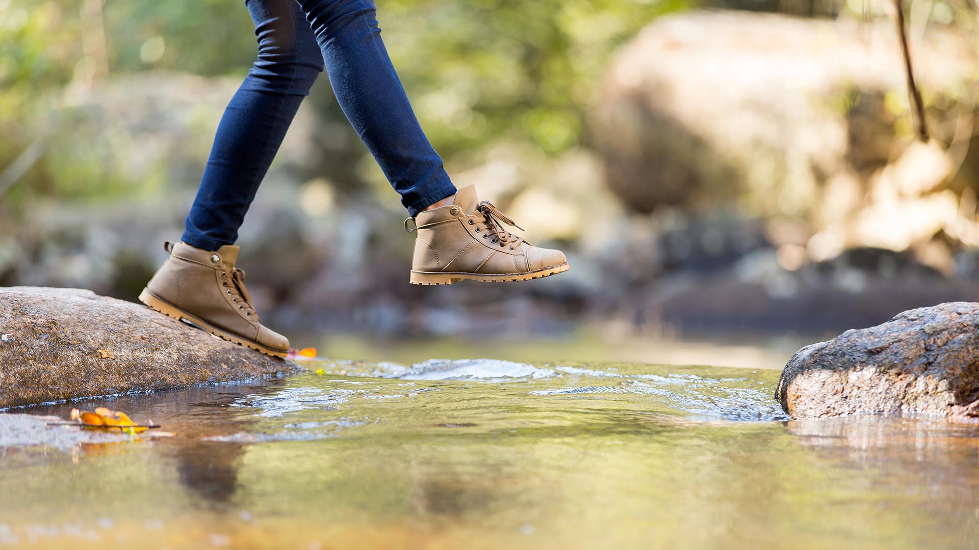 Person walking over a stream on a hike.