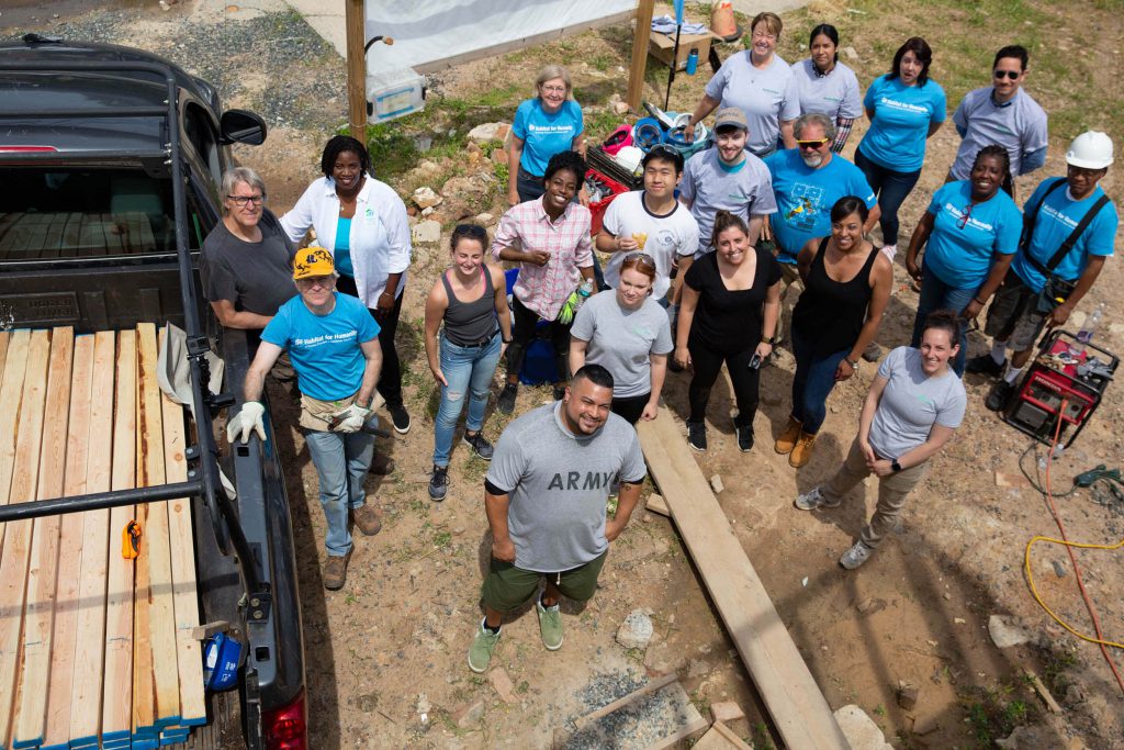 A team of diverse people working on a habitat for humanity house.