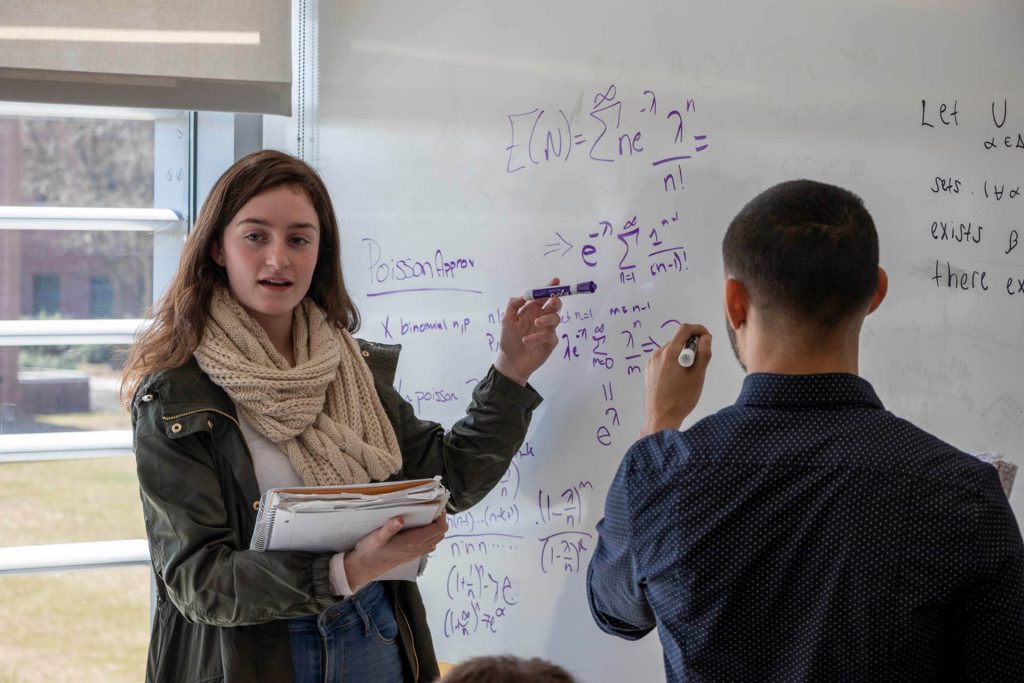 A student and teacher working on a white board.